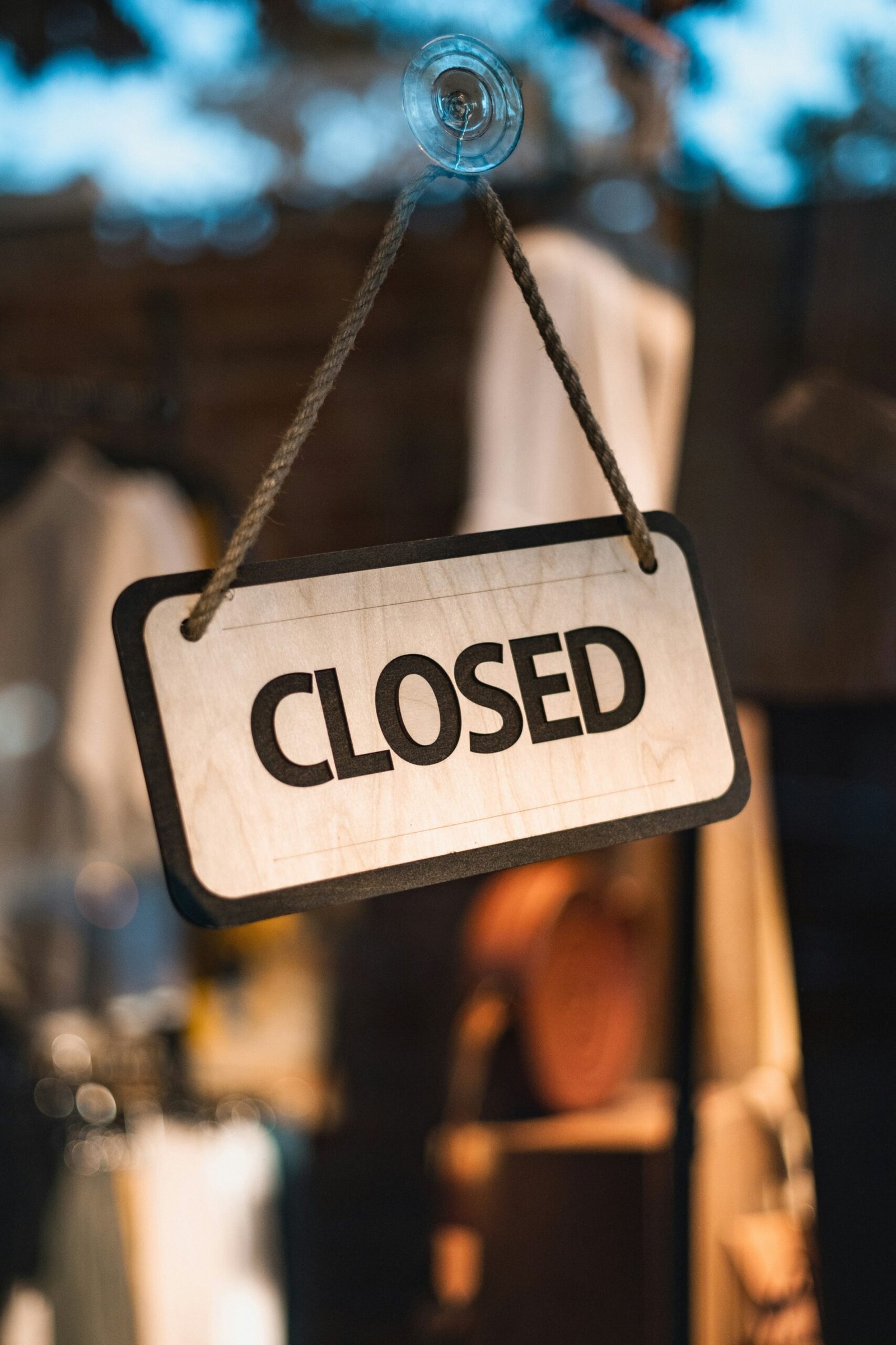 A close up of a closed sign hanging from a rope